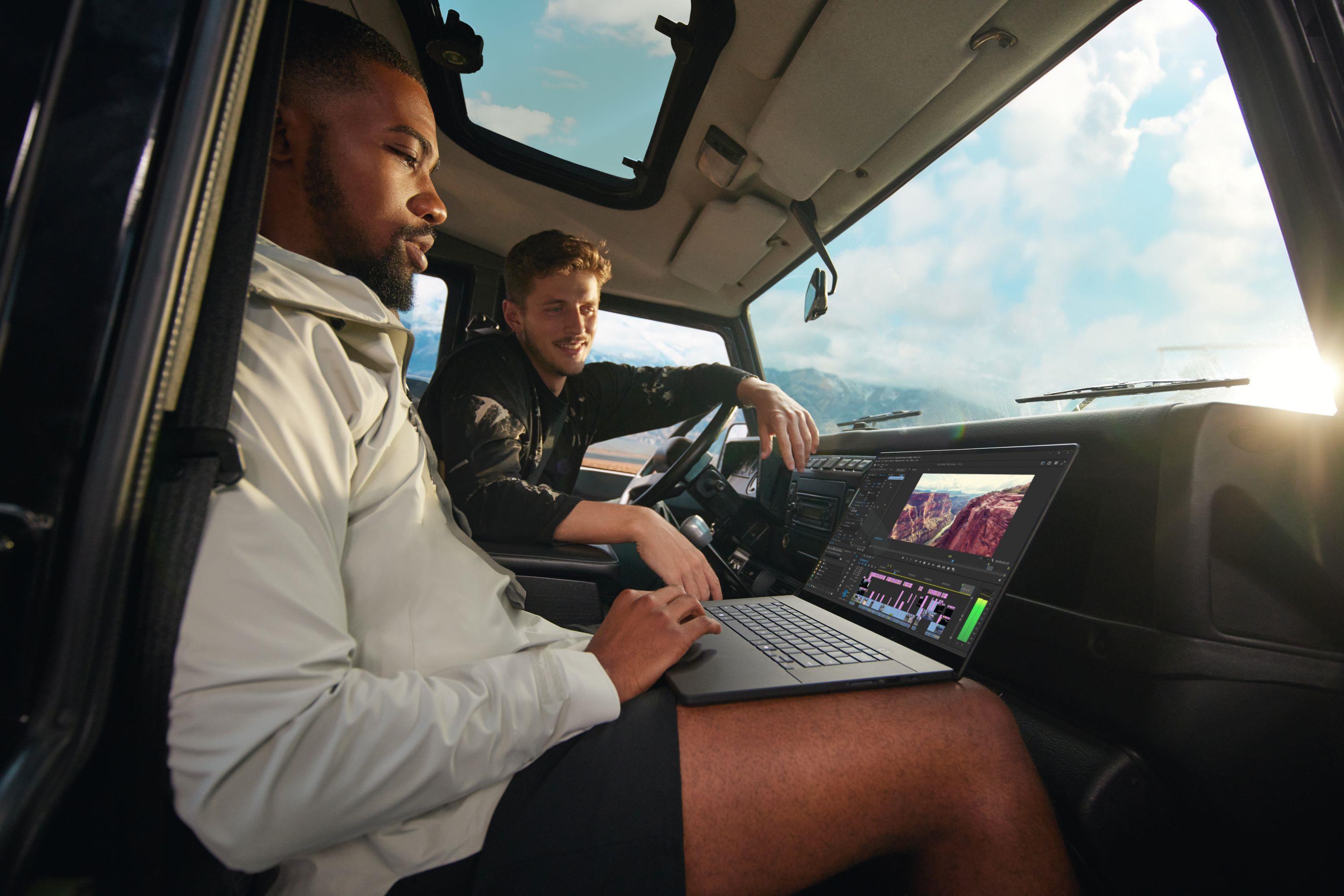 Two people in a parked car using an ASUS laptop